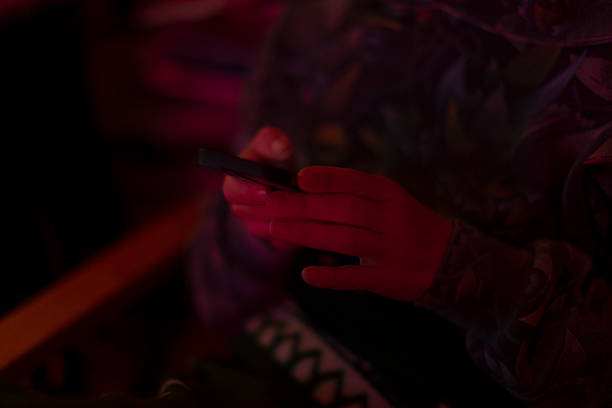 istock Person Using Smartphone in Low Light with Colorful Background 2216802545