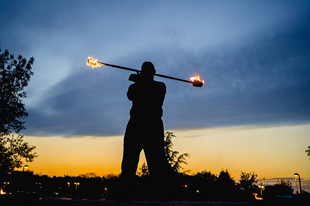 istock Fire performer skillfully twirling flaming staff at sunset 2216802602