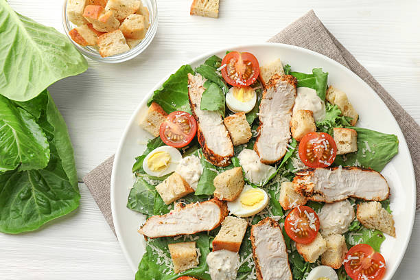 istock Tasty Caesar salad with chicken and tomatoes on white wooden table, flat lay 2216803968