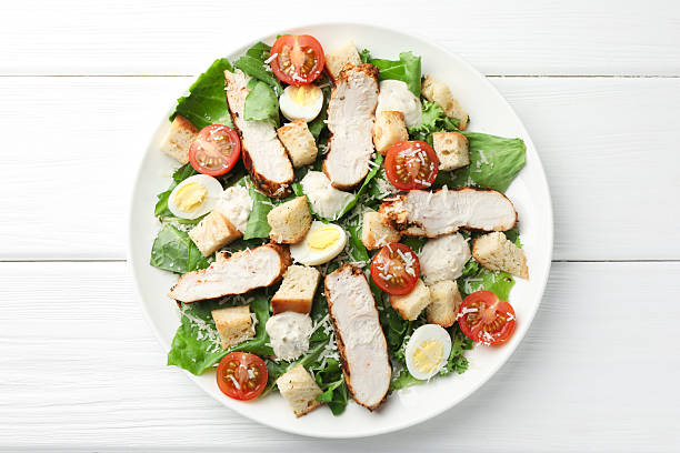 istock Tasty Caesar salad with chicken and tomatoes on white wooden table, top view 2216803976