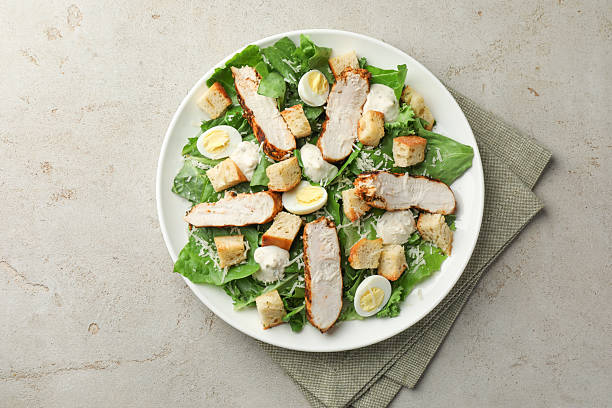 istock Tasty Caesar salad with chicken on light grey table, top view 2216804017