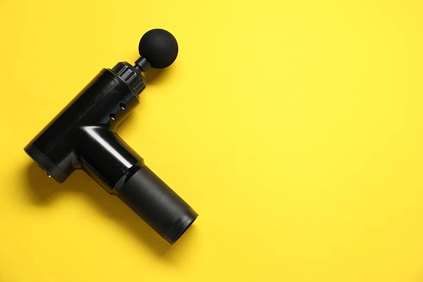 istock One black percussive massager on yellow background, top view. Space for text 2216804485