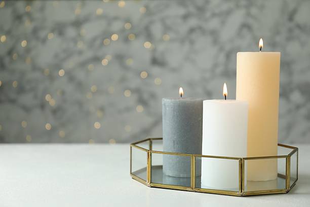 istock Beautiful burning candles on white table against blurred lights, space for text 2216806675