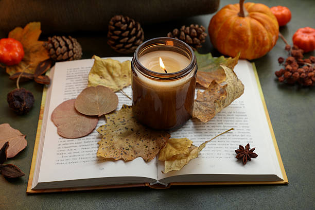istock Burning candle, autumn decor and open book on green background 2216806872