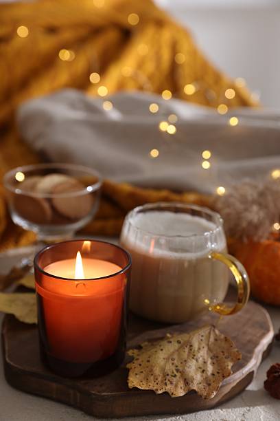 istock Burning candle, cocoa and dry leaves on table, closeup. Autumn atmosphere 2216806921