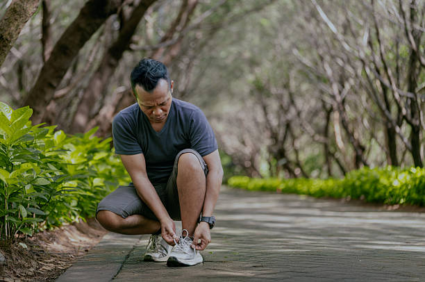 istock Asian man tying laces on his sneakers before jogging at park, empty space for text. 2216810521