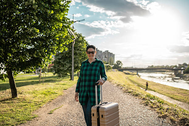 Woman Enjoying a Pleasant Walk Through Park Path With Suitcase in Hand