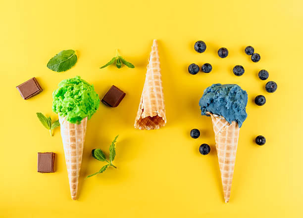 istock Three ice cream cones, one empty, one with blueberry flavor and one with mint flavor  on a yellow background 2216818895