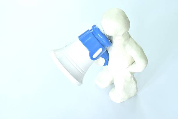 clay man model holding toy plastic white and blue megaphone and speaking isolated on white background