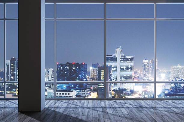 istock Modern empty room interior with large windows overlooking illuminated city skyline at night, showcasing sleek design and architectural background.. 3D Rendering 2216829367