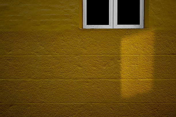Yellow concrete walls and small windows with sunlight