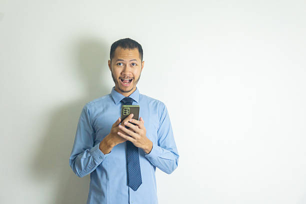 istock Businessman with necktie surprised while holding smartphone 2216836365