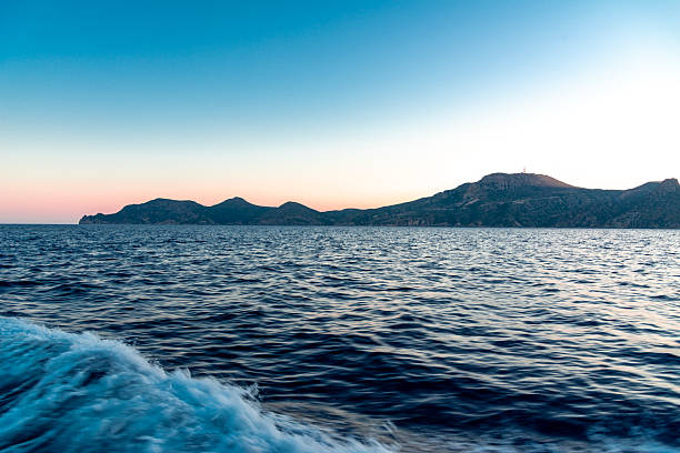 View from a boat leaving with high speed, in the back  island at sunset
