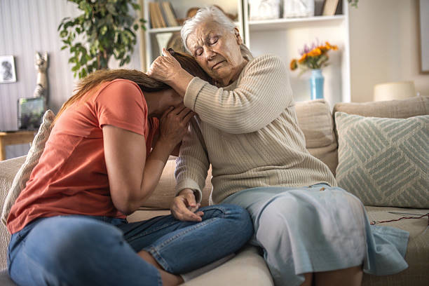 Attractive middle aged woman embrace little preschool frustrated kid sitting on couch together at home. Loving grandma supports disappointed grandson sympathizing, make peace after scold concept