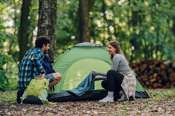 istock Happy couple setting up tent while camping in forest 2216842591