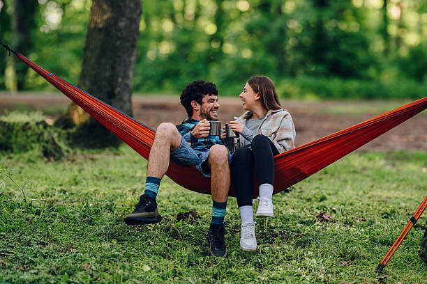 istock Hikers relaxing in hammock, enjoying hot beverages in lush forest 2216842772