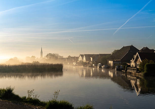 Iconic Dutch polder landscape Early foggy morning  A village in the fog near the waterfront.