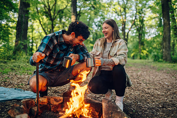 istock Hikers laughing and drinking by campfire in forest 2216843395