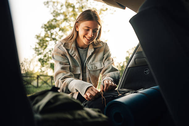 istock Young woman packing backpack in car trunk for camping trip 2216843399
