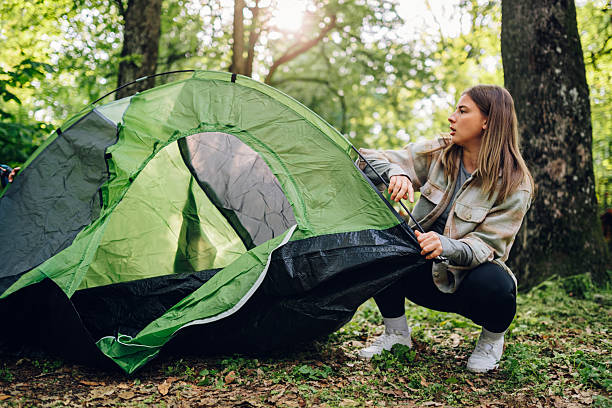 istock Young woman setting up tent in a forest campsite during summer vacation 2216843563