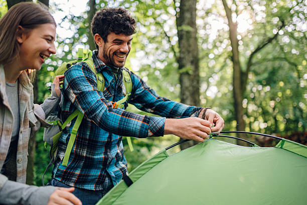 istock Hikers smiling and setting up tent in forest 2216843571