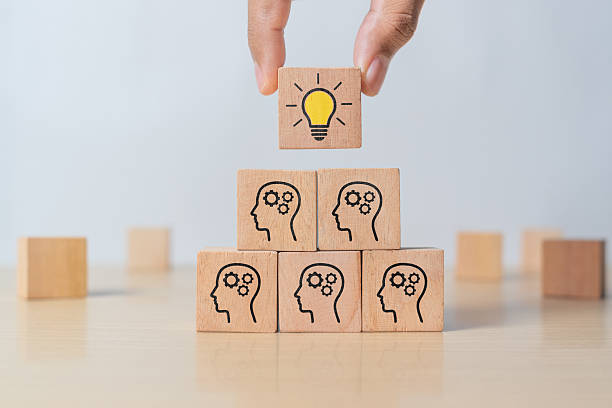 istock Concept creative idea and innovation. Hand picked wooden cube block with head human symbol and light bulb icon 2216847028