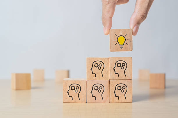 istock Concept creative idea and innovation. Hand picked wooden cube block with head human symbol and light bulb icon 2216847089