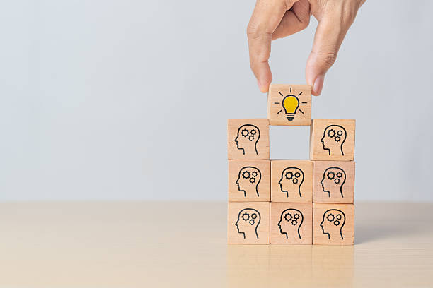 istock Concept creative idea and innovation. Hand picking a wooden cube block featuring a human head symbol and light bulb icon 2216847746