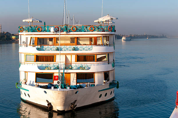 A multi-deck river cruise boat sails on the calm waters of the Nile River, offering scenic views and leisure travel experiences in Egypt.