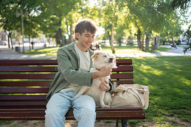 istock Young man enjoying time with a dog on a park bench 2216849013