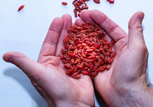 Dried Goji berries on white background and human hands close-up