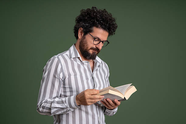 Mid adult man reading a book over green background