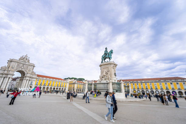 Lisbon, Portugal - November 15, 2024: A lively square with a bronze equestrian statue of King Jose I, an ornate arch, and historic yellow buildings. Arch commemorates post-earthquake rebuilding.