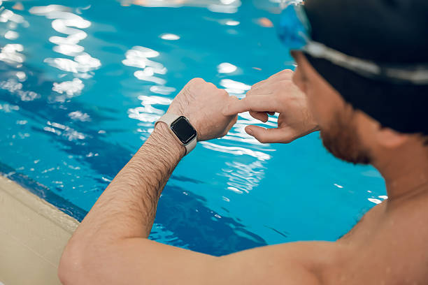 istock Man having a workout in the swimming pool and looking at his watch 2216859924