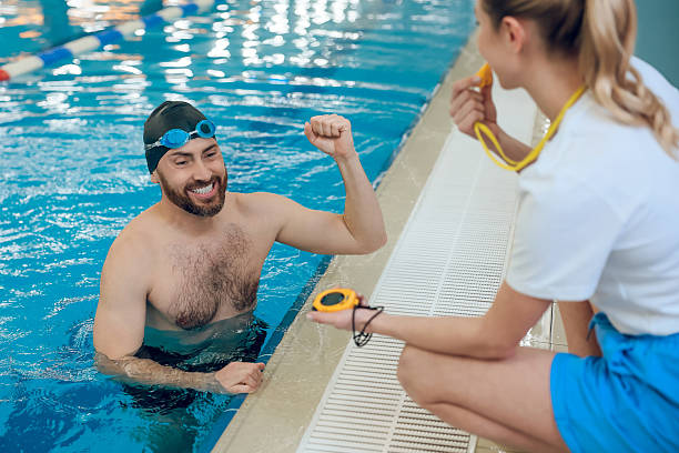 istock Man having a workout in the swimming pool and talking with his coach 2216859939