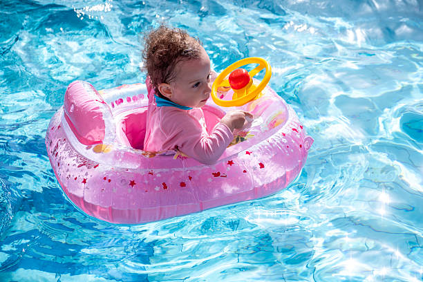 istock Toddler Floating in Pink Inflatable Pool Float in Bright Blue Water 2216865790