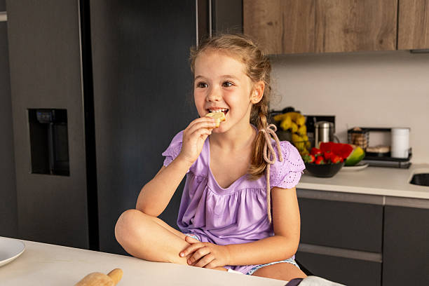 istock Smiling girl eating bread in a modern kitchen 2216867040
