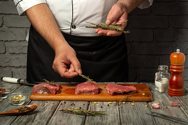 istock In a rustic kitchen, a chef carefully seasons raw meat with fresh herbs, showcasing culinary techniques and the use of quality ingredients. The atmosphere reflects a dedication to cooking 2216869127