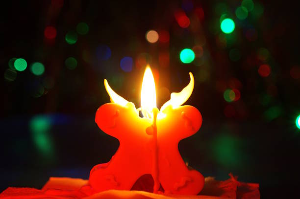 A burning Christmas candle in a dark room.