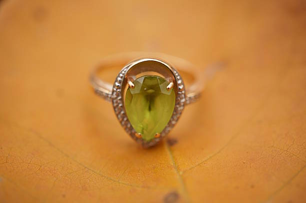 A precious ring with chrysolite on the background of an autumn leaf.