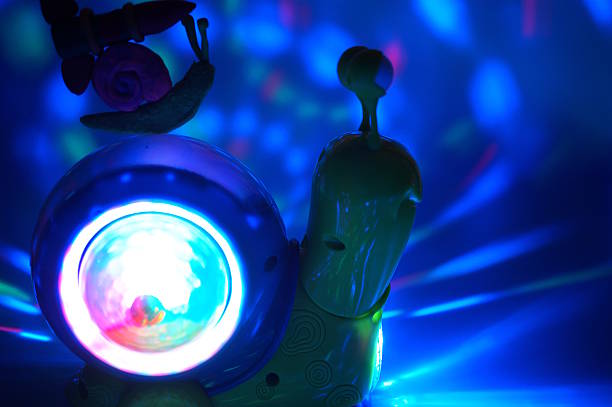 istock A snail with a plasticine rocket is located on another glowing toy snail. Blue background. 2216874002