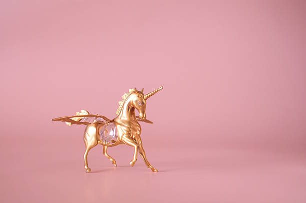 A unicorn figurine on a pink background.