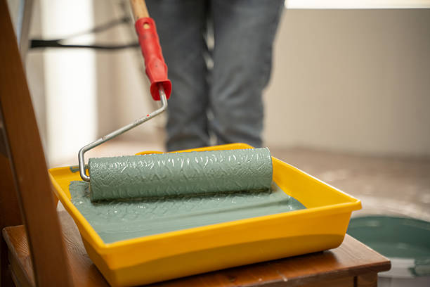 istock Painter dipping paint roller in tray with green paint during home renovation 2216877089