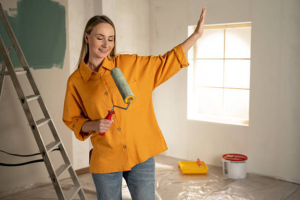 istock Woman painting wall having fun singing with paint roller 2216877372