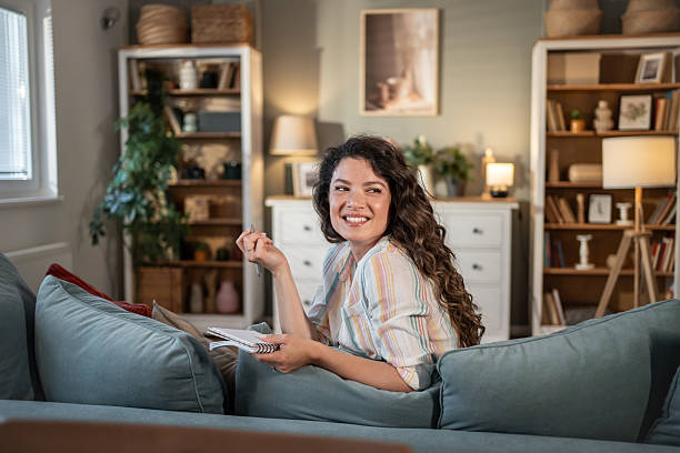 istock Young woman taking notes while relaxing on sofa at home 2216886254