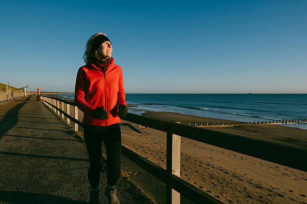 Senior woman running on the pedestrian walkway below the Esplanade just north of Aberdeen, Scotland, just after dawn..