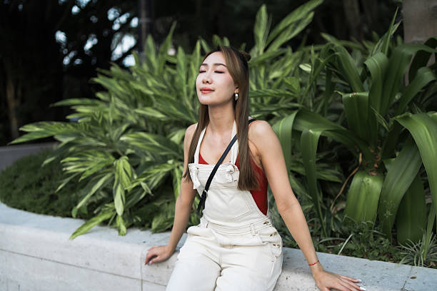 Beautiful woman outdoors in nature breathing fresh air with closed eyes, mindful meditation in nature.