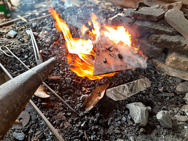 Close-up of steel being heated in a traditional Indonesian blacksmith forge with open fire and charcoal. Old-style metalworking process