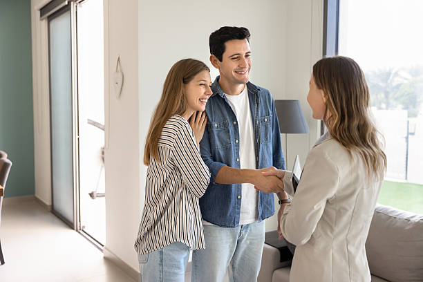 istock Happy young couple shaking hands with real estate agent 2216901567