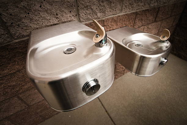 Classic American stainless steel drinking fountains installed at different heights. Iconic traditional drinking fountains typically found in schools, playgrounds, public spaces and institutions.